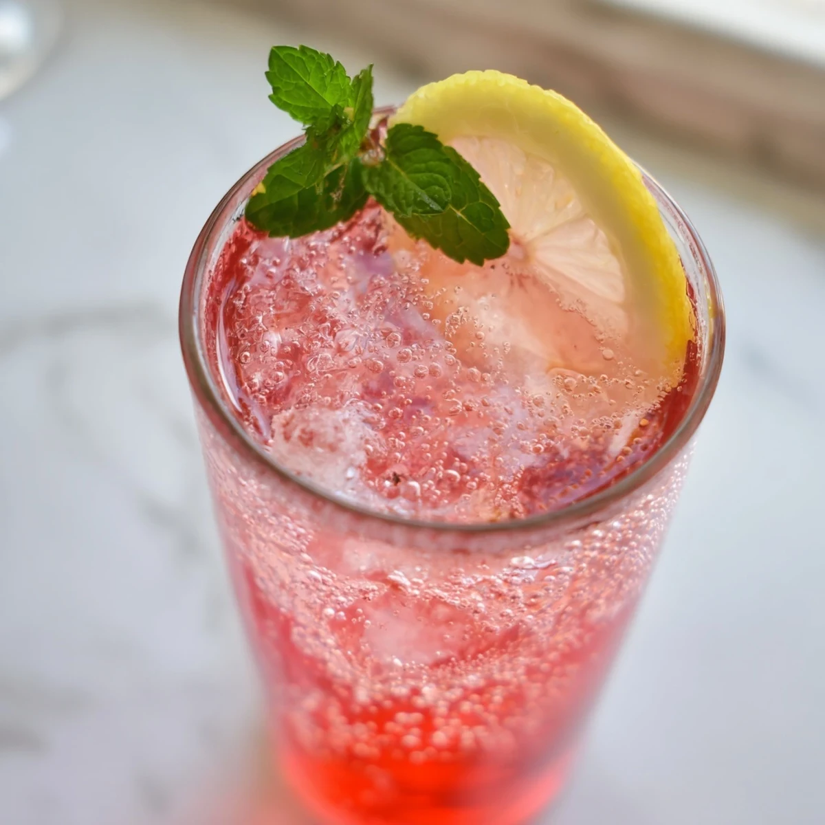 Chilled honey lemon pink soda served over ice with fresh mint garnish