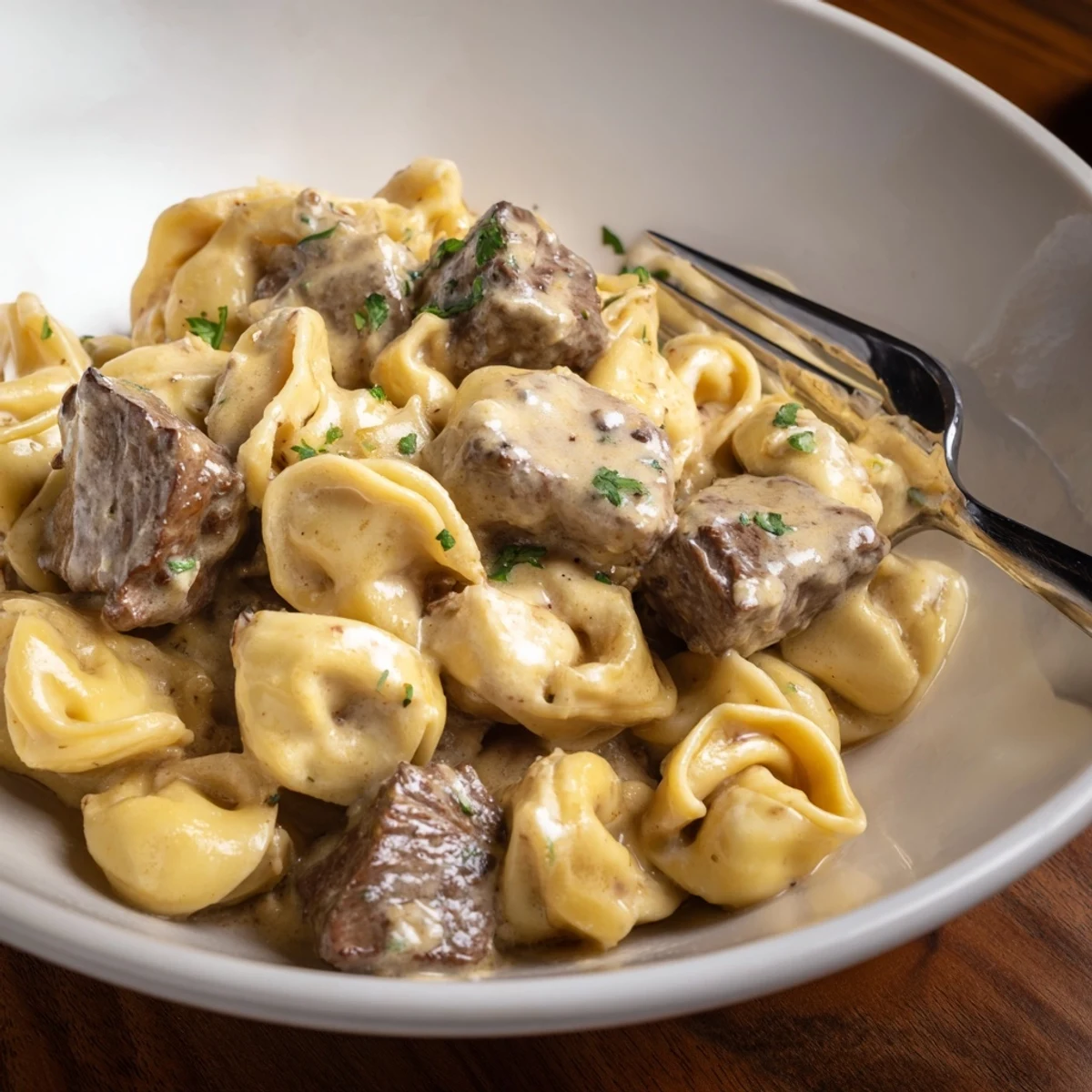 Golden garlic steak tortellini in a creamy white sauce garnished with fresh parsley  