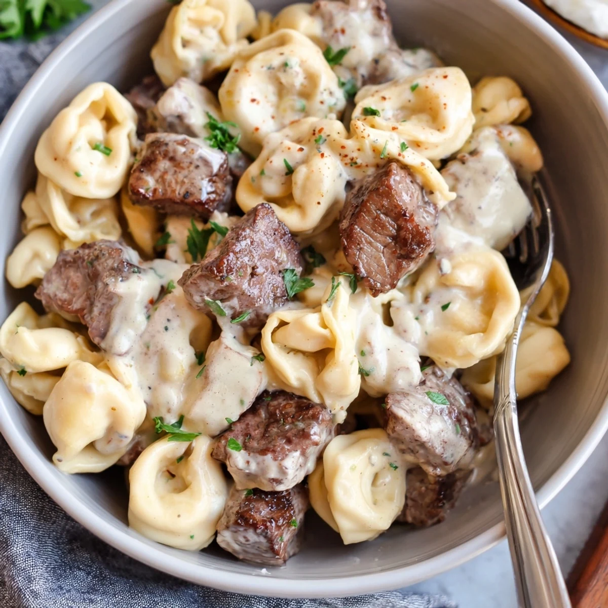 Hearty bowl of garlic steak tortellini featuring tender beef and al dente pasta swimming in sauce