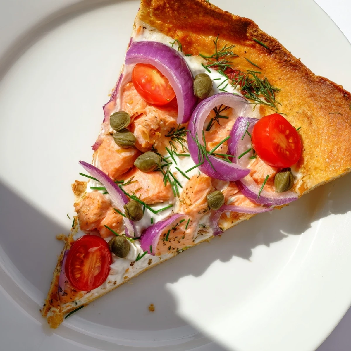 Golden brown tortilla pizza with flaked salmon, capers, and dill garnish baked until bubbling and cheesy.  
