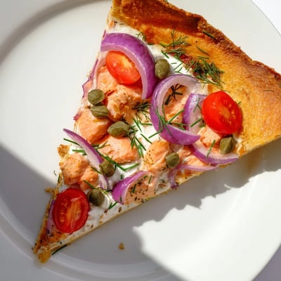 Golden brown tortilla pizza with flaked salmon, capers, and dill garnish baked until bubbling and cheesy.  